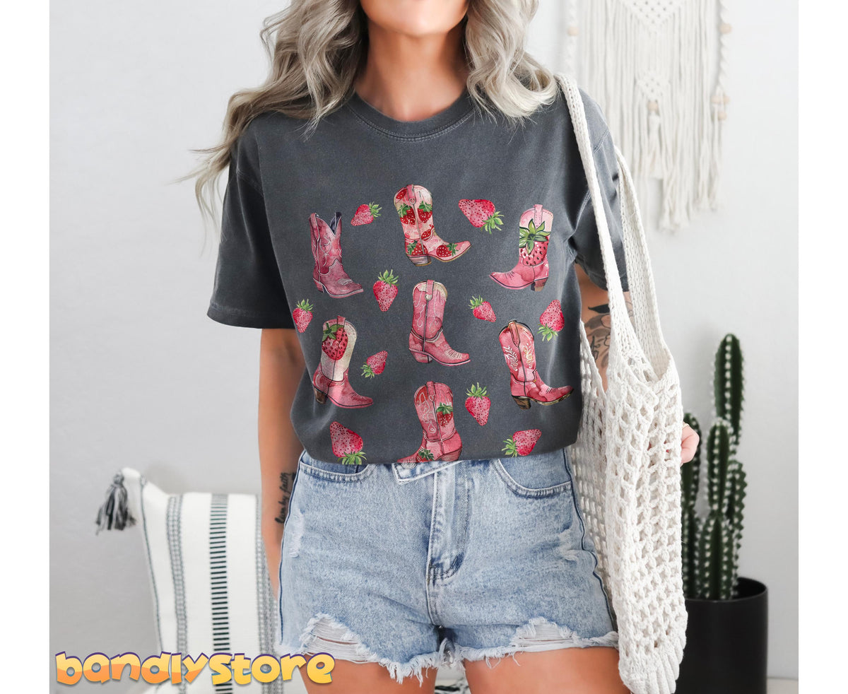 Strawberry Cowgirl Boots T-Shirt in pepper worn by a person facing forward indoors next to a cactus and macrame bag.