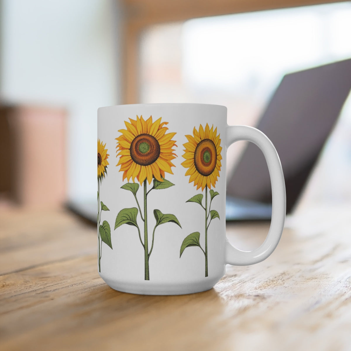 Sunflower Mug on a wooden table with a laptop blurred behind, angled to show the handle.