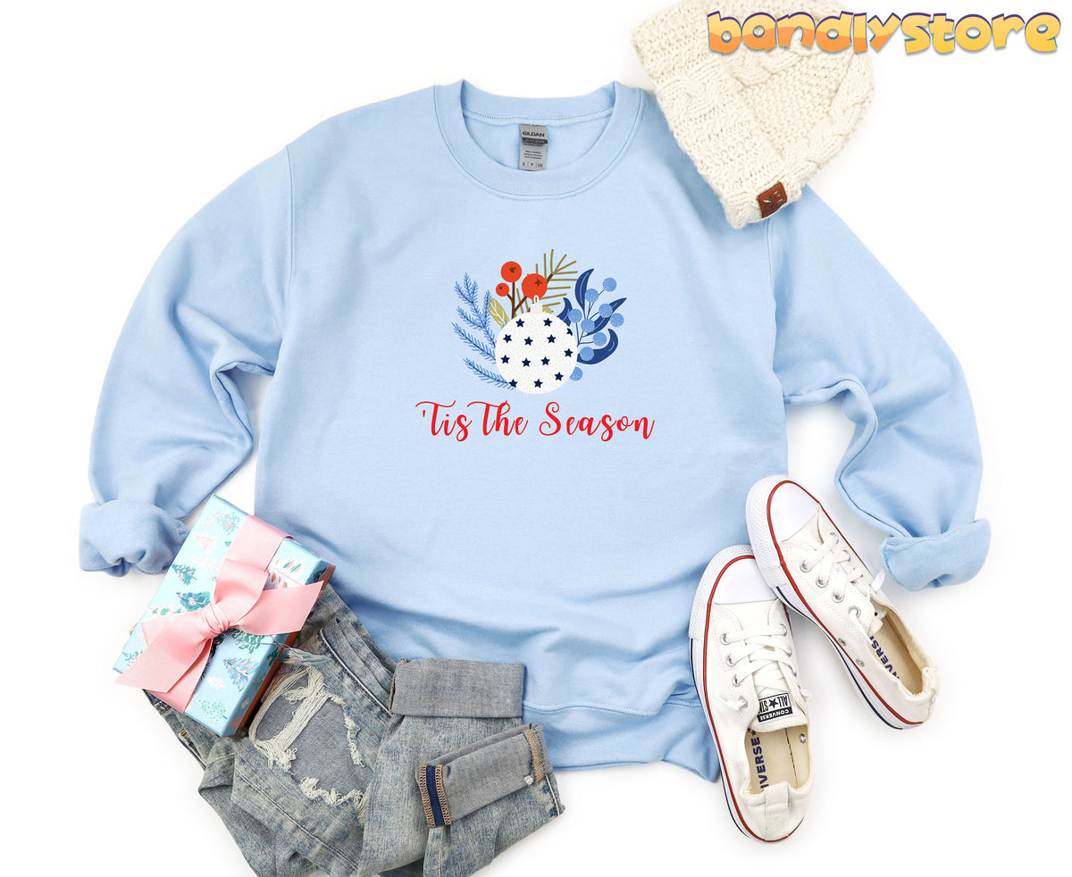 Tis The Season Sweatshirt in light blue laid flat from above with beanie, jeans, sneakers and gift.