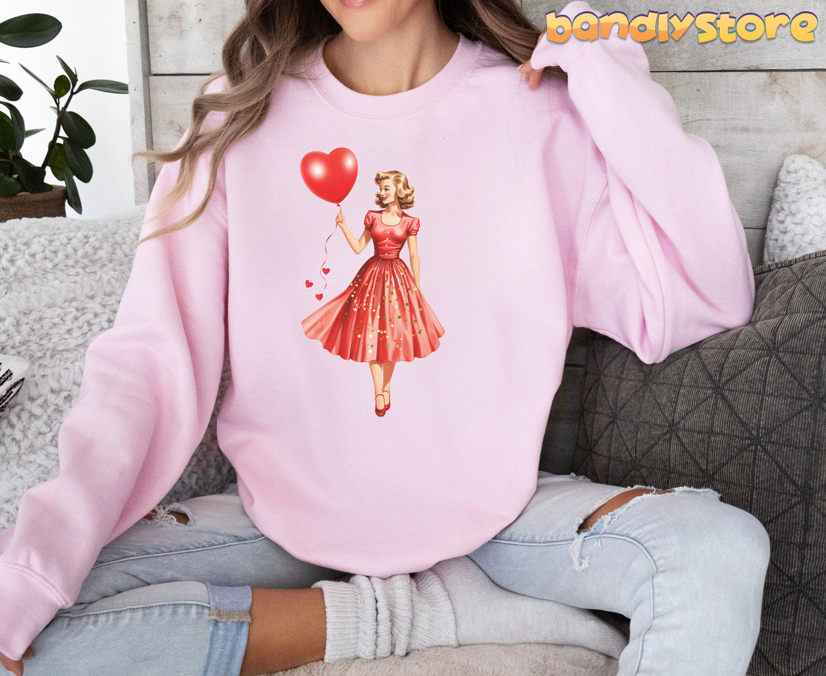 Valentine Girl Sweatshirt in light pink on a person seated front-facing on a sofa with pillows and plant.