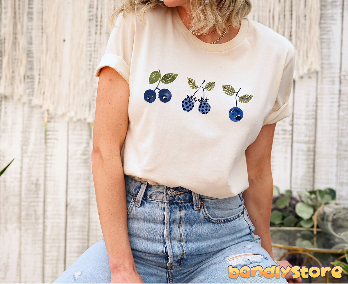 Vintage Blueberry T-Shirt in natural on a seated person against white wood wall with macrame and plants.