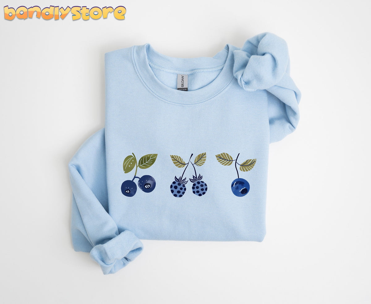 Vintage Blue Berries Sweatshirt in light blue, folded flat on white with berry print across the chest.