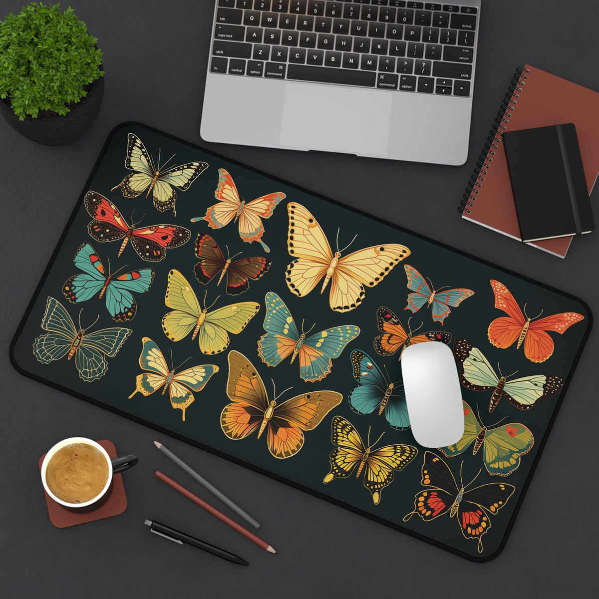 Vintage Butterflies Desk Mat 12 × 22 inches from above on a desk with laptop, plant, coffee, notebooks, pens and mouse.