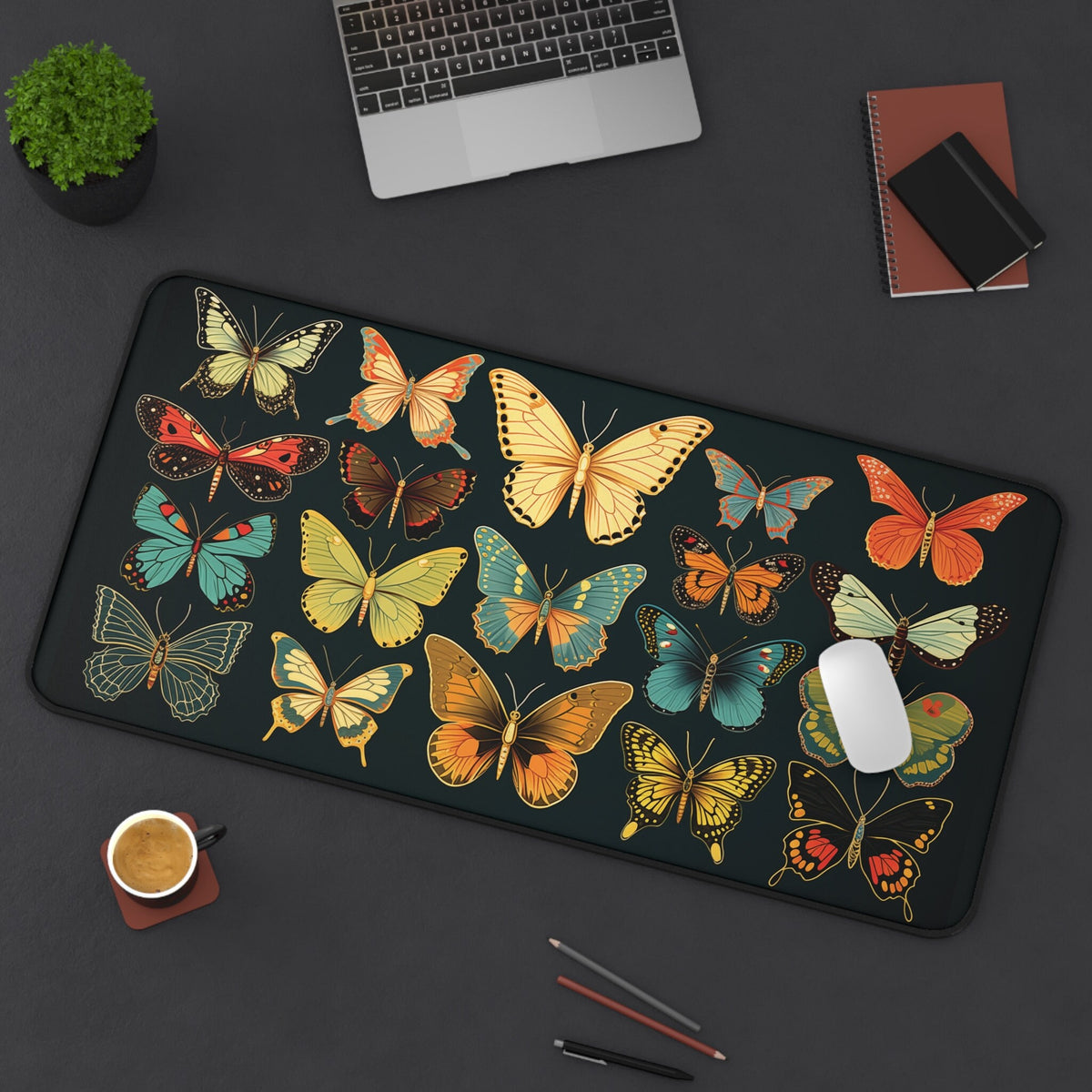 Vintage Butterflies Desk Mat, 16 × 32 inches, top-down on dark desk beside laptop, plant, coffee, notebooks and pens.