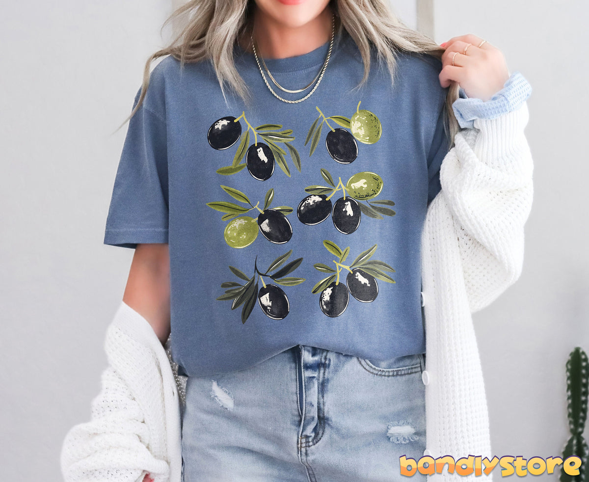 Vintage Olives T-Shirt in Blue Jean, worn front-facing with white cardigan and jeans against a plain wall.