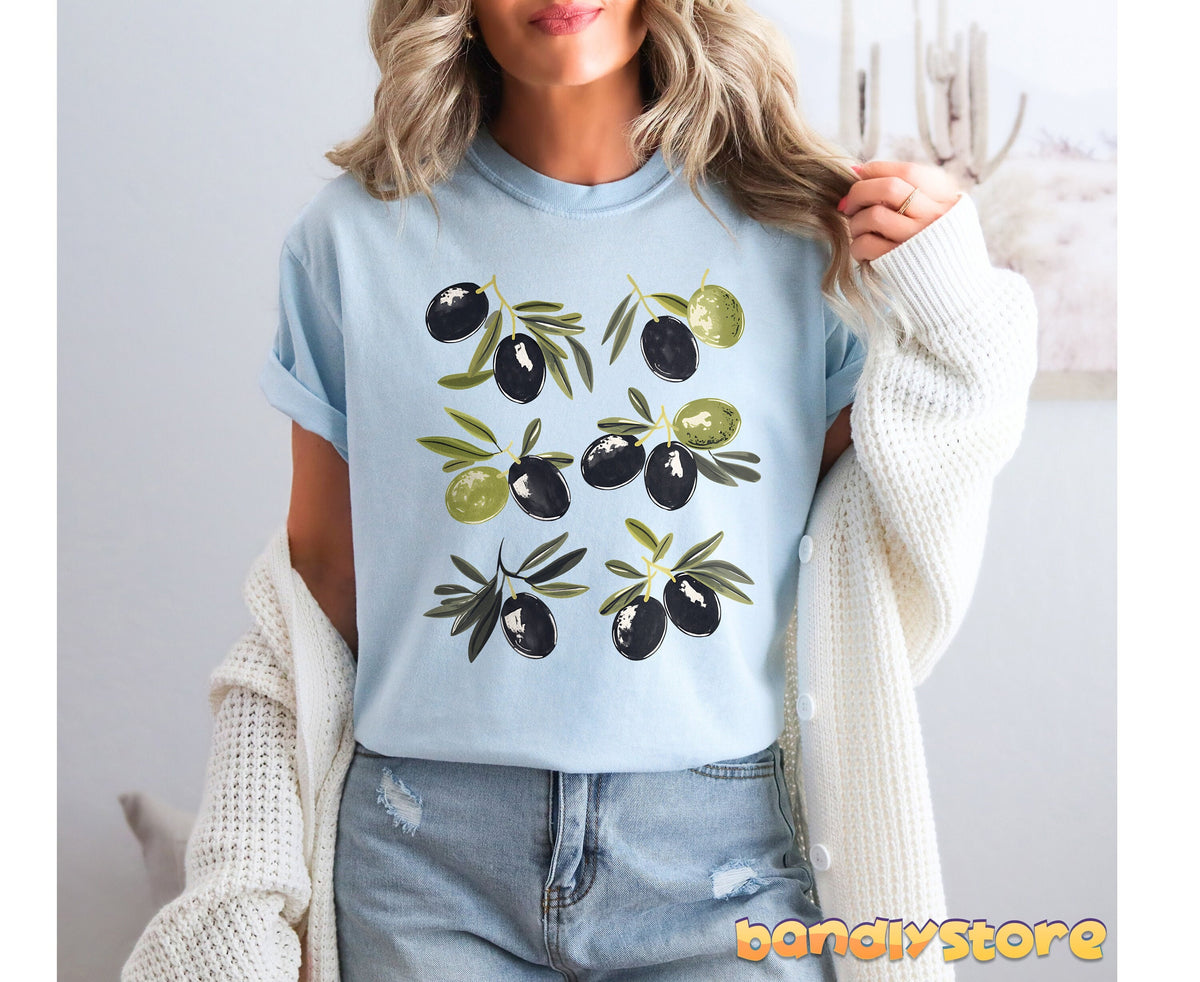 Vintage Olives T-Shirt in chambray worn front-on by a model holding a white cardigan over jeans by cactus wall art.