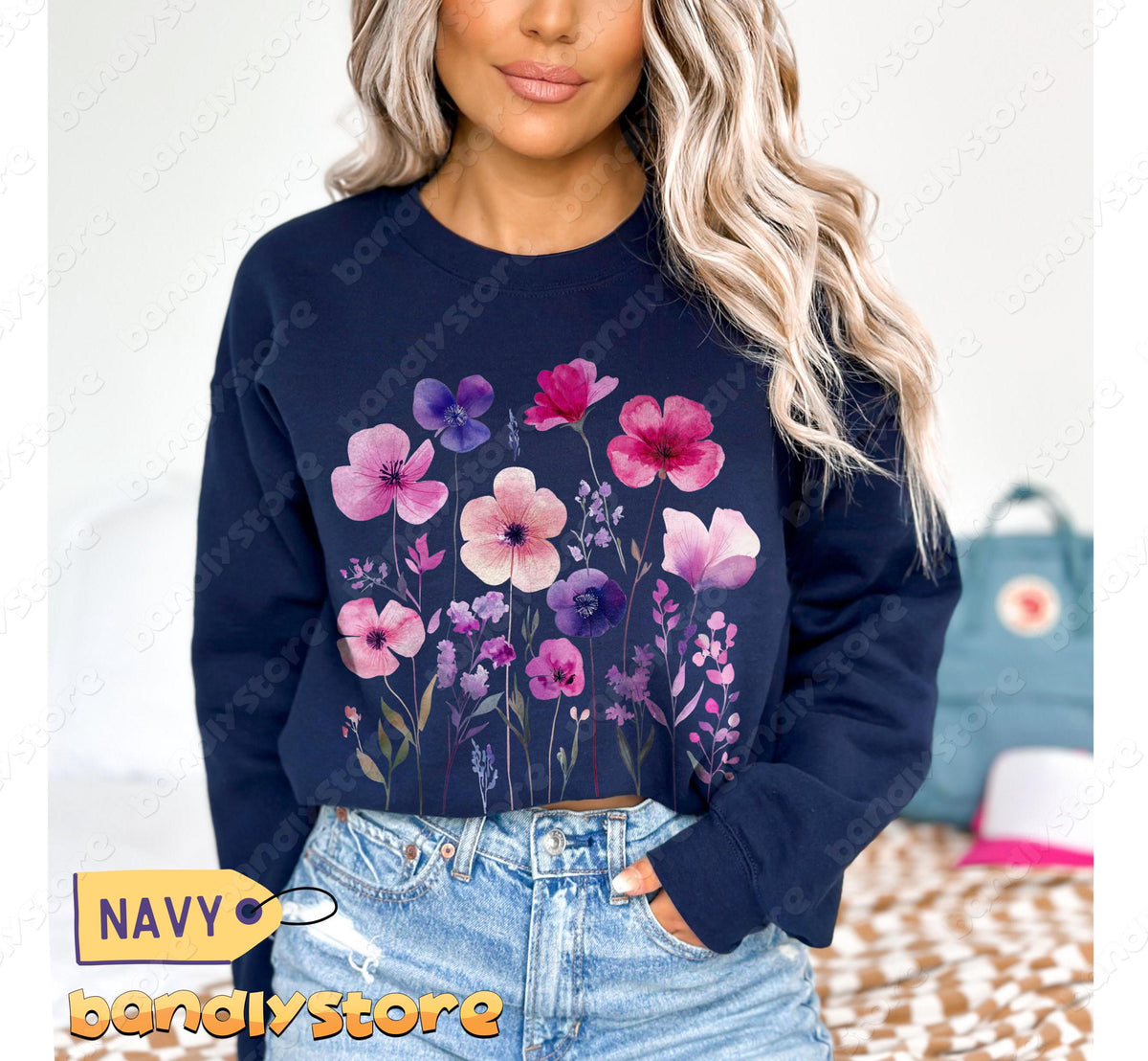 Vintage Wildflowers Sweatshirt in navy on model from front, indoor setting with jeans and backpack nearby.