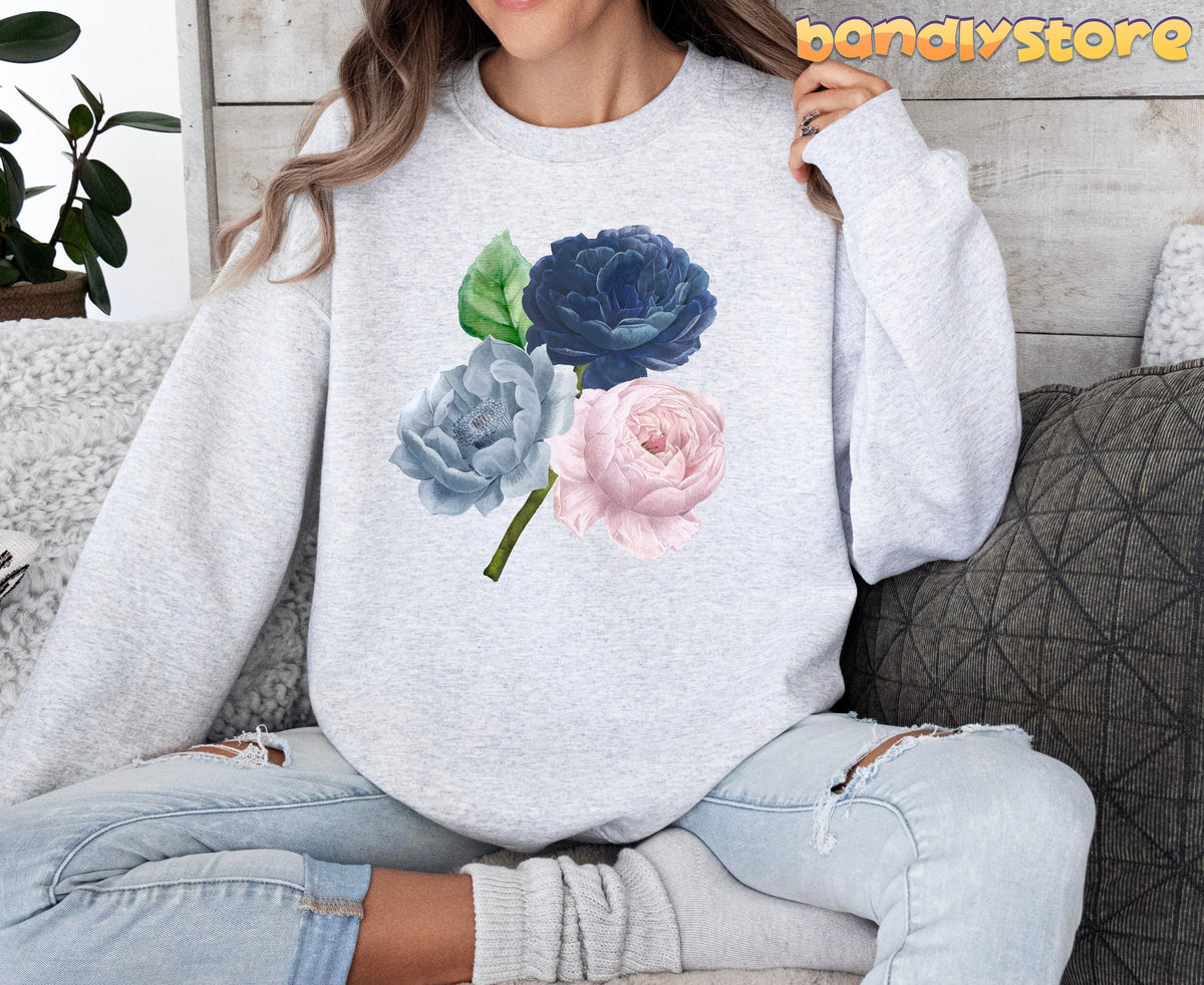 Vintage Roses Sweatshirt in ash on a seated person against wood wall with plant and pillows.