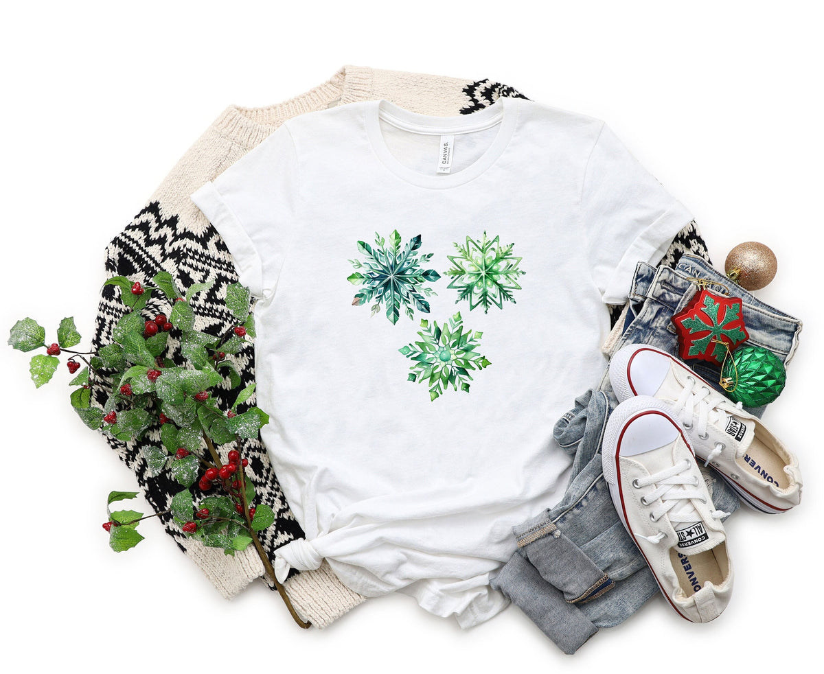 Watercolor Snowflakes T-Shirt white flat lay with holly, sweater, jeans, sneakers and ornaments.