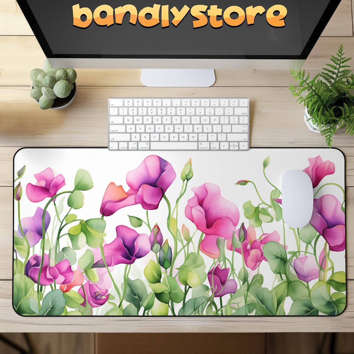 Watercolor Sweet Pea Flowers Desk Mat on a wooden desk with monitor, keyboard, mouse and potted plants in top-down view.
