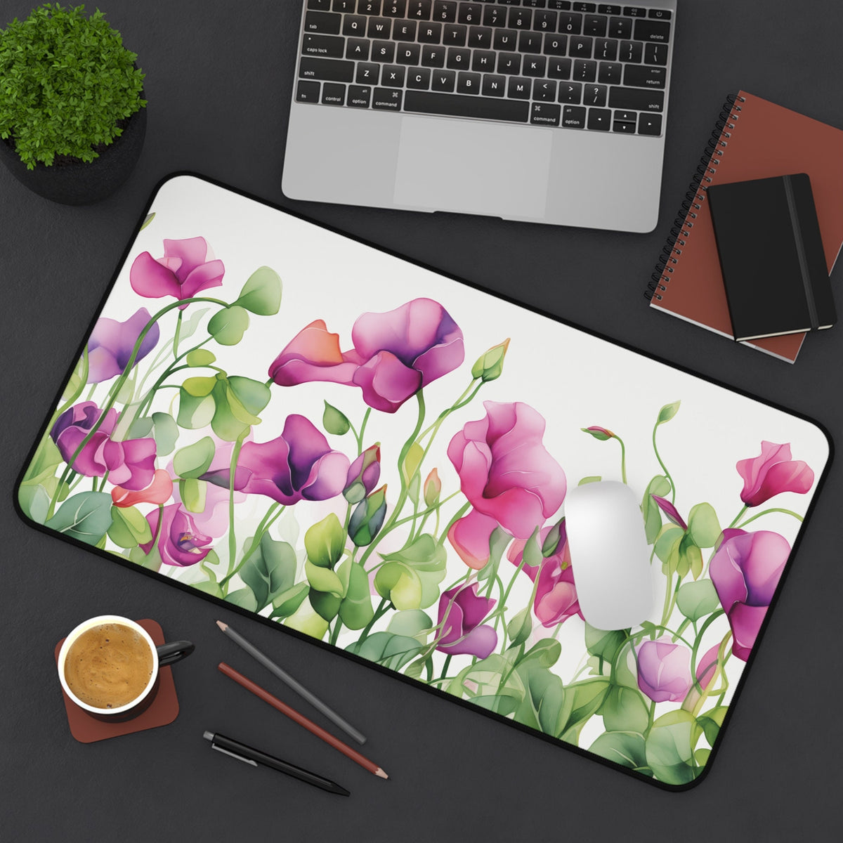 Watercolor Sweet Pea Flowers Desk Mat on a dark desk with laptop, mouse, coffee, plant and notebooks, 12 × 22 inches.